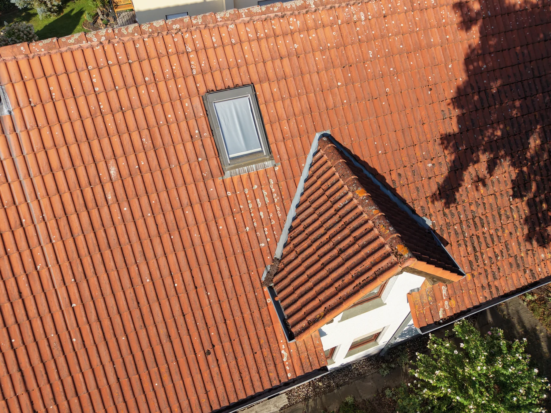 Übersichtsaufnahme eines Ziegeldachs mit Dachfenster und Gaube aus der Foto-Drohne